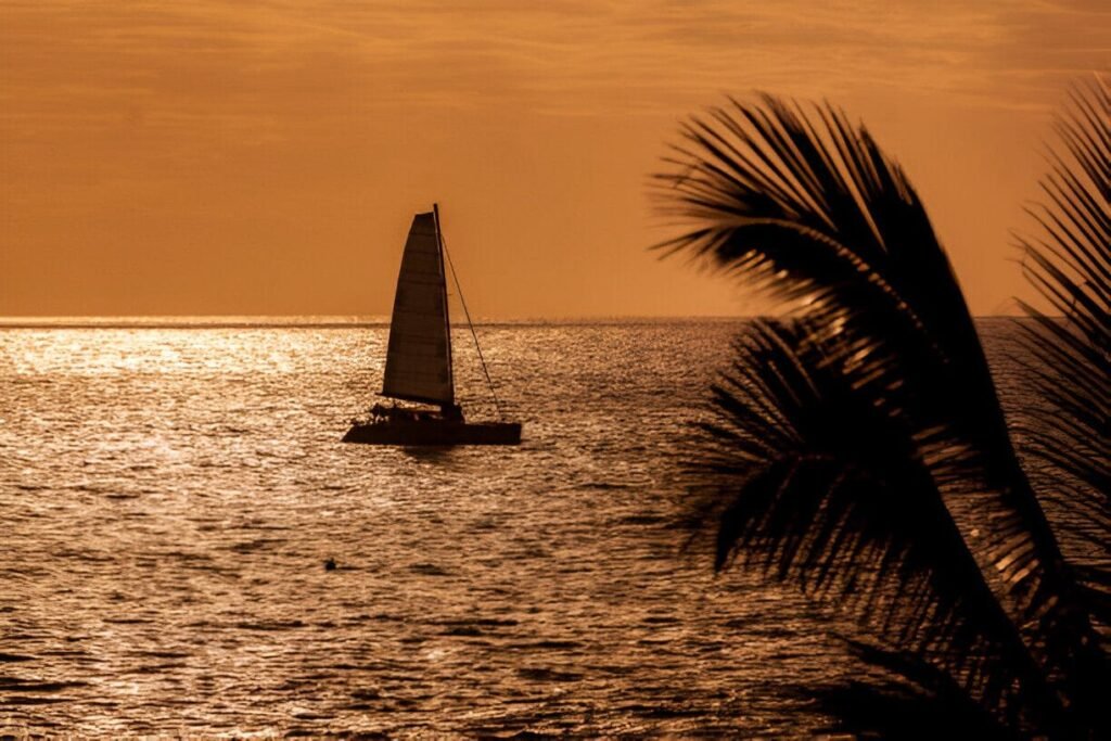 Catamaran sailing along Aruba’s coastline during a golden sunset