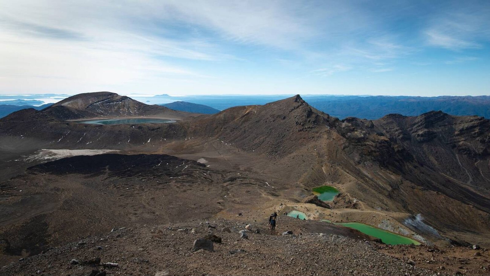 Hikers crossing emerald lakes and volcanic terrain on Tongariro Alpine Crossing
