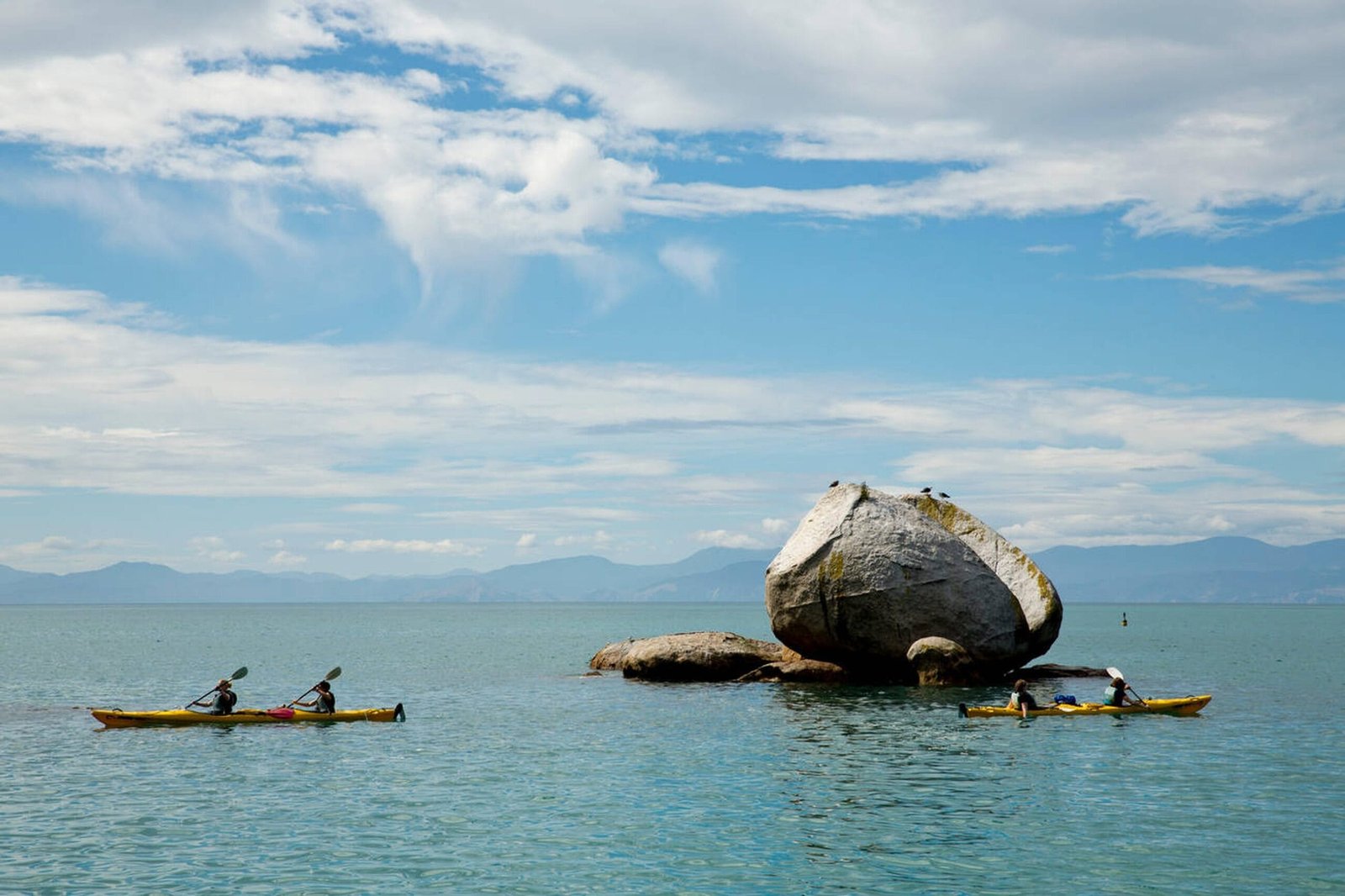 Kayakers paddling near Split Apple Rock in Abel Tasman National Park.